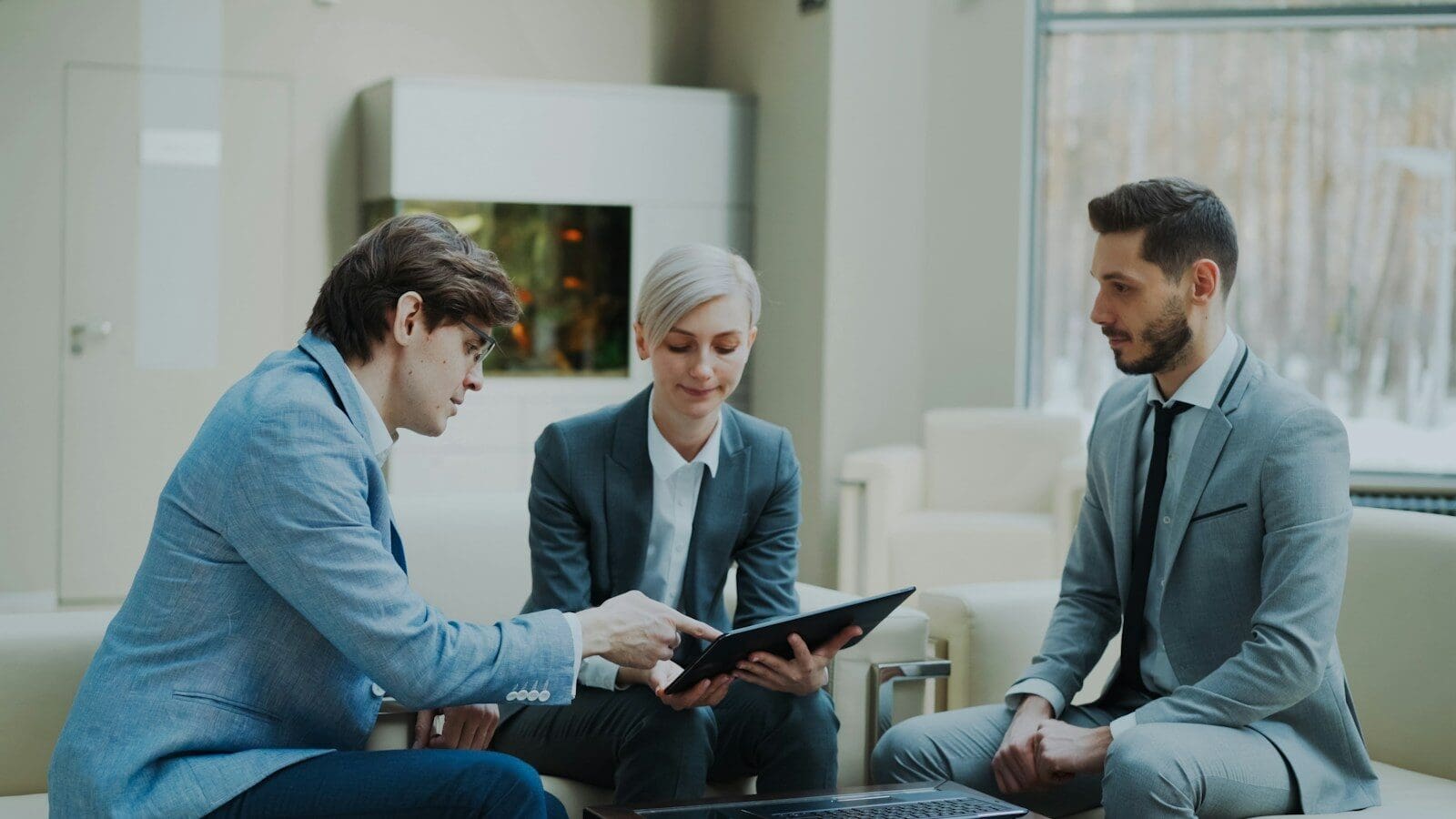 Three professionals discussing a tablet in a modern office